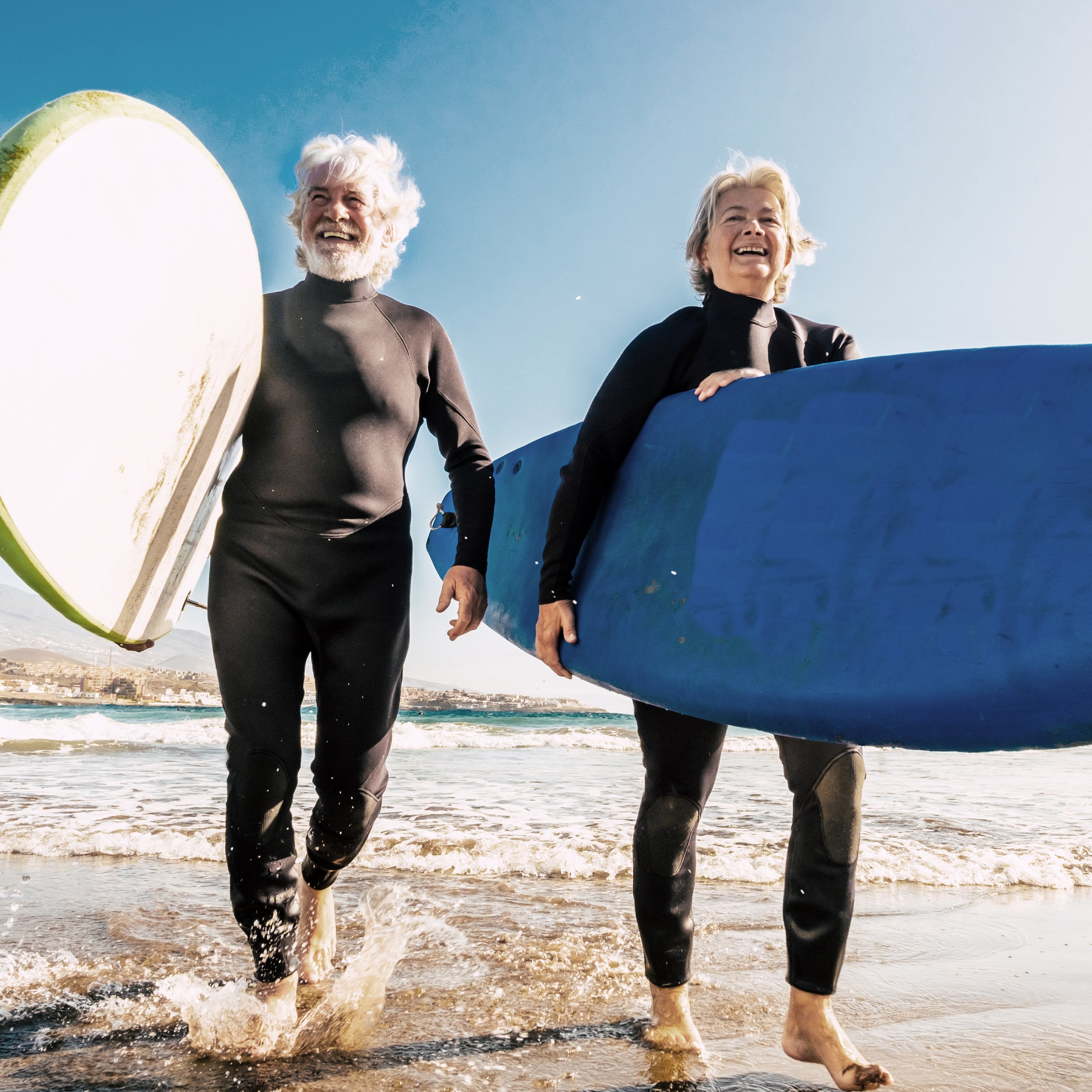 Zwei ältere Menschen mit Surfbrettern am Meer